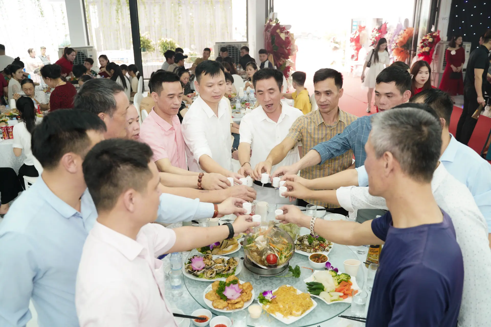 Cả bàn khách nâng ly rượu 9 Chum trong tiệc khai trương của một đối tác