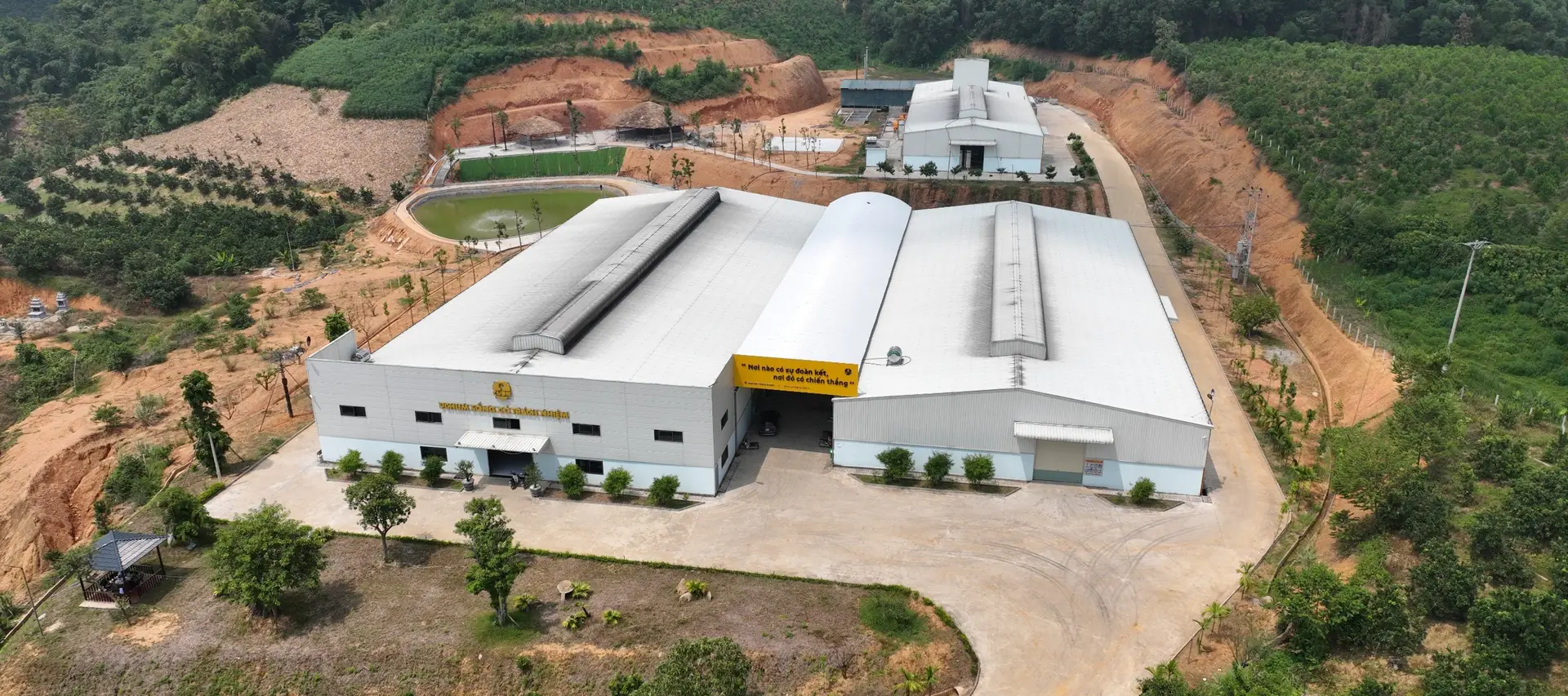 Nhà máy 9 Chum nhìn từ trên cao năm 2022, ba dãy nhà xưởng mái trắng giữa đồi cây ở Yên Sơn